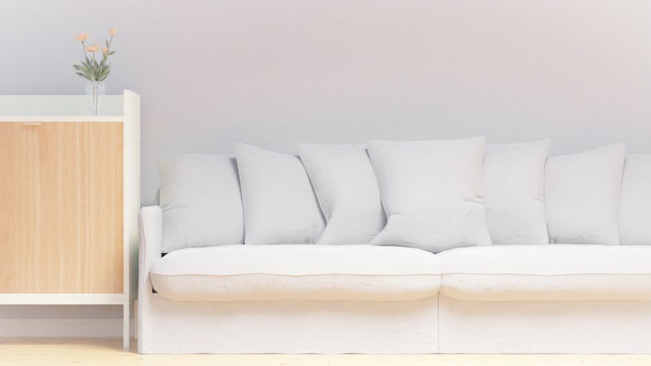 A serene minimalist living room featuring a white sofa with plush cushions and a side table.